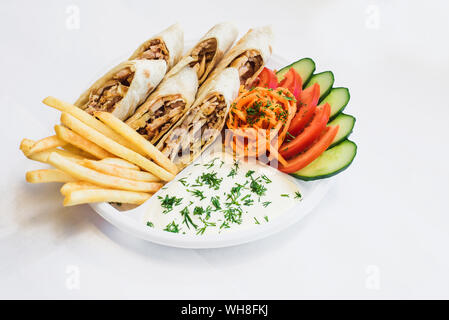 Shawarma isolato in una piastra con ombra. Oriental cibo fatto da carne di pollo, pomodori, coreano carote, patate fritte, i cetrioli in pane pita. Foto Stock