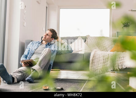 Metà uomo adulto seduto sul pavimento, con tavoletta digitale Foto Stock