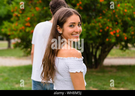 Coppia giovane in un parco, donna che guarda la fotocamera Foto Stock