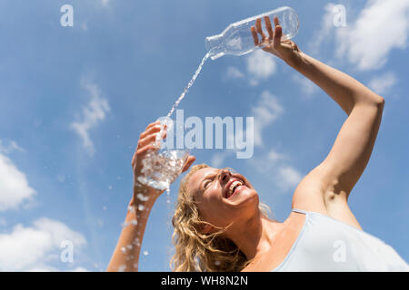 Donna versando acqua in un bicchiere esterno a basso angolo di visione Foto Stock