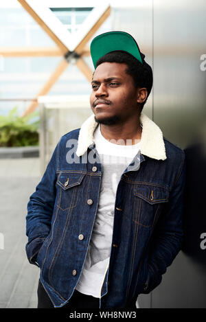 Ritratto di uomo denim da indossare giacca e cappello da baseball guardando a distanza Foto Stock