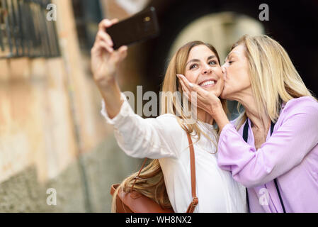 Donna felice di prendere una selfie con sua madre in città Foto Stock