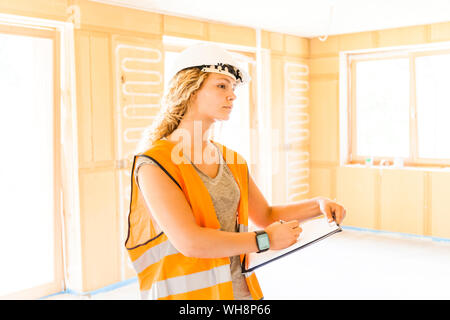 Giovane donna il controllo della costruzione di una nuova casa in legno Foto Stock