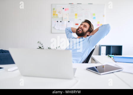 Ridendo imprenditore seduto alla scrivania Foto Stock