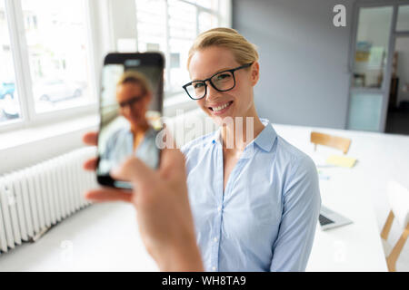 Immagine dello smartphone di giovane imprenditrice in office Foto Stock
