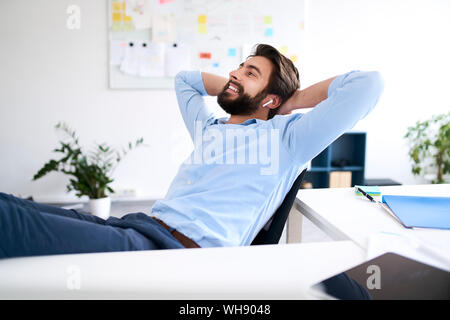 Imprenditore sorridente seduto alla scrivania Foto Stock