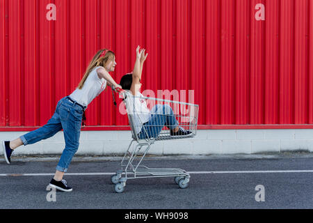 Suore con il carrello nella parte anteriore della parete rossa Foto Stock