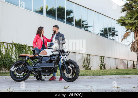 Coppia con caschi moto in piedi accanto al moto Foto Stock