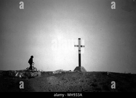 Bambini aborigeni sulla bici accanto a croce a Hermannsburg missione storica impresa luterana Foto Stock