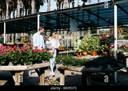 Madre, padre e figlia a piedi attorno a un centro giardino Foto Stock