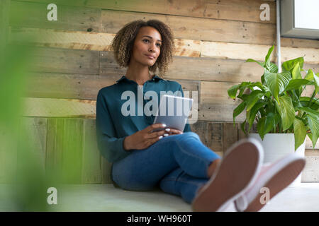 Ritratto di pensieroso giovane donna con tavoletta digitale