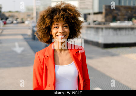 Ritratto di sorridente giovane donna indossa red suit coat Foto Stock