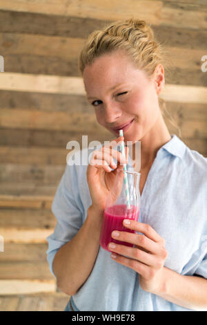 Sorridente donna bionda bere un frullato Foto Stock