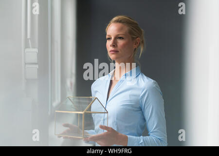 Giovane imprenditrice azienda casa di vetro modello Foto Stock