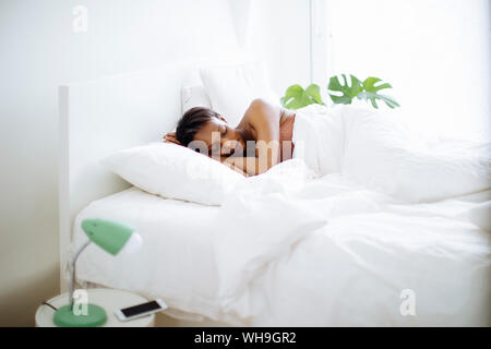 Donna che dorme nel letto di casa Foto Stock