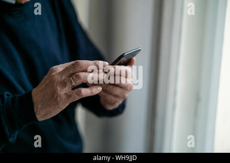Close-up di senior uomo tramite telefono cellulare a casa Foto Stock