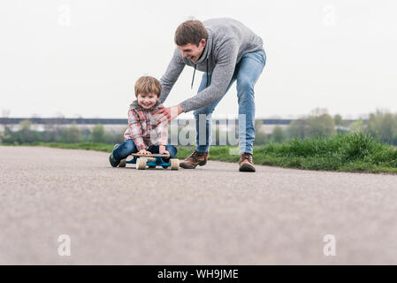 Padre e figlio divertirsi giocando con lo skateboard all'aperto Foto Stock