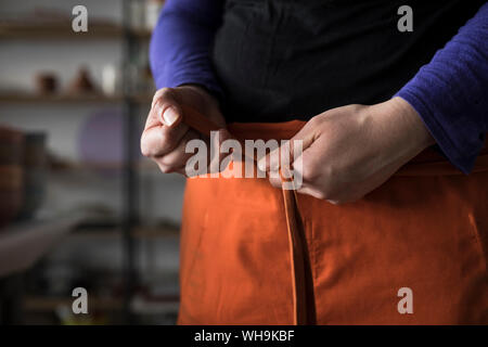 Donna di mani grembiule di legatura Foto Stock