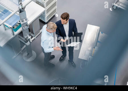 Due imprenditori con appunti parlando in una fabbrica Foto Stock