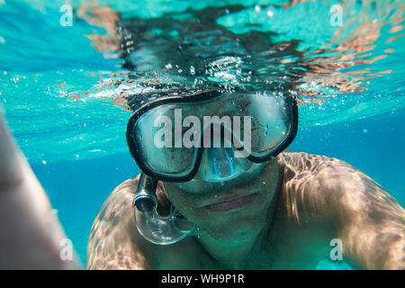 Ritratto di uomo con gli occhiali di immersioni e snorkeling tenendo selfie sotto l'acqua Foto Stock