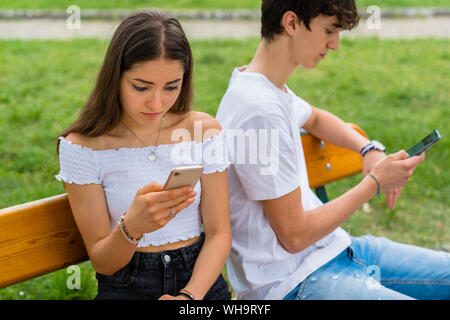 Coppia giovane utilizza lo smartphone in un parco Foto Stock