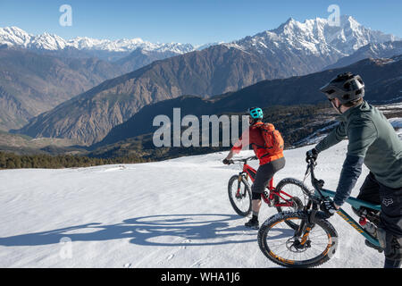 I ciclisti di montagna scendono una coperta di neve pendenza in Himalaya con vedute della gamma Langtang nella distanza, Nepal, Asia Foto Stock