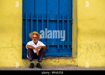 Un cubano anziani seduti su un uscio di fumare un sigaro, Trinidad, Sancti Spiritus Provincia, Cuba, West Indies, dei Caraibi e America centrale Foto Stock