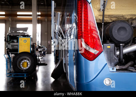 Autobus e camion in attesa per il servizio e la manutenzione in garage. automobile e concetto di trasporto. Foto Stock