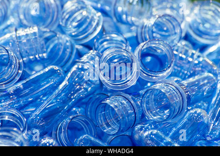 Gruppo di preforme in PET di plastica trasparente blu è pronto per la produzione di bottiglie in plastica per il confezionamento di bevande idriche nell'industria delle bevande Foto Stock