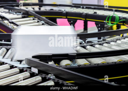 Bianco scatola di cartone di imballaggio del prodotto in movimento sul nastro trasportatore della macchina impacchettatrice automatica nella fabbrica di produzione pronto per la distribuzione a marke Foto Stock