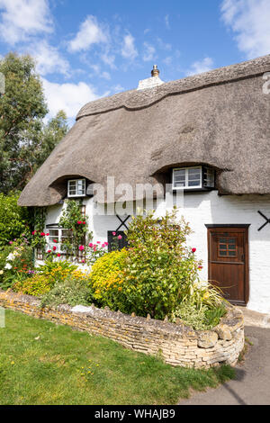 La deliziosa chiesa di paglia Cottage in un angolo del sagrato a Vescovo di Cleeve, GLOUCESTERSHIRE REGNO UNITO Foto Stock