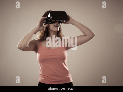 Stupiti donna prendere l'esperienza utilizzando cuffie VR occhiali, sensazione entusiasti di simulazione, esplorare la realtà virtuale compiendo gesti interagenti con Foto Stock