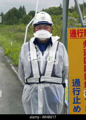 Visita Minamisoma, nel quartiere Haramachiku, una città duramente colpita dalla radiazione perdita dalla Fukushima Daiichi e daini centrali nucleari dopo il terremoto e lo tsunami. Guardia di sicurezza evitando il traffico proveniente da entrare insicure zone radioattive. Foto Stock