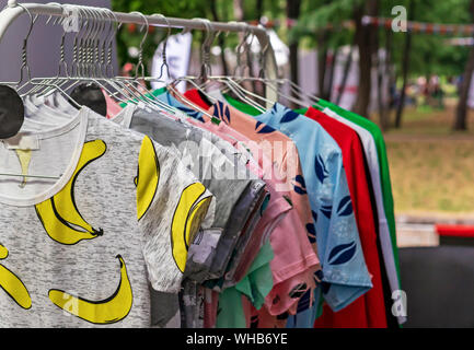 Vestiti su appendiabiti in negozio. T-shirt su staffe di metallo. Foto Stock