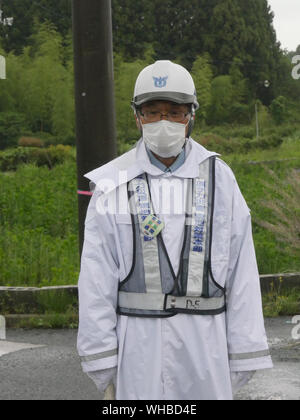 Visita Minamisoma, nel quartiere Haramachiku, una città duramente colpita dalla radiazione perdita dalla Fukushima Daiichi e daini centrali nucleari dopo il terremoto e lo tsunami. Guardia di sicurezza evitando il traffico proveniente da entrare insicure zone radioattive. Foto Stock