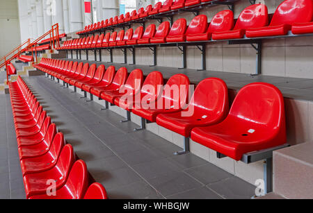 Rosso in plastica posti allo stadio. Tribune fan. Posti a sedere per gli spettatori allo stadio. Foto Stock
