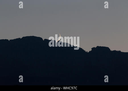 New Moon Rising sulla cresta della montagna. Foto Stock