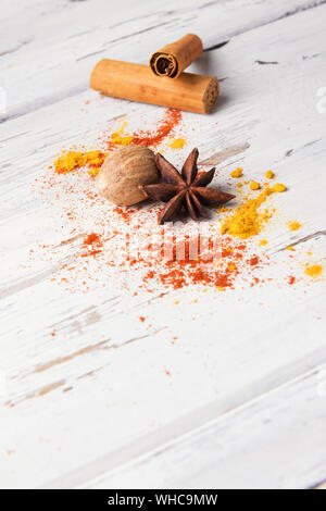 Bellissima cibo sullo sfondo delle spezie: set di anice stellato, curcuma, il bastoncino di cannella, noce moscata in bianco sullo sfondo di legno. Spezie, ingredienti per la preparazione mu Foto Stock