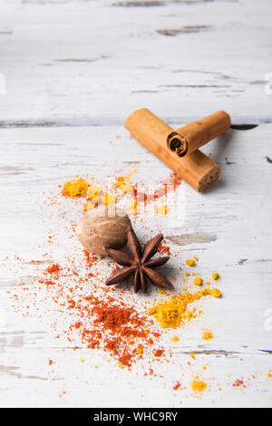 Bellissima cibo sullo sfondo delle spezie: set di anice stellato, curcuma, il bastoncino di cannella, noce moscata in bianco sullo sfondo di legno. Spezie, ingredienti per la preparazione mu Foto Stock