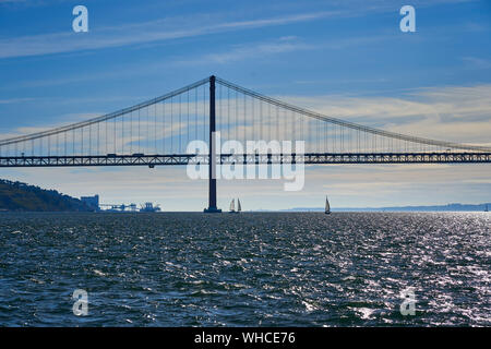 Barca a vela sul fiume Tago con Ponte 25 de Abril in background Lisbona, Portogallo. Foto Stock