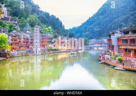 Fenghuang, Cina. Settembre 13, 2015. Edifici circondano entrambi i lati del Tuo Jiang fiume di Fenghuang antica cittadina al tramonto nella provincia del Hunan in Cina. Foto Stock