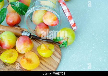 Fresh cut prugne sul tavolo della cucina e della scheda sfondo blu. Frutta fresca. Foto Stock
