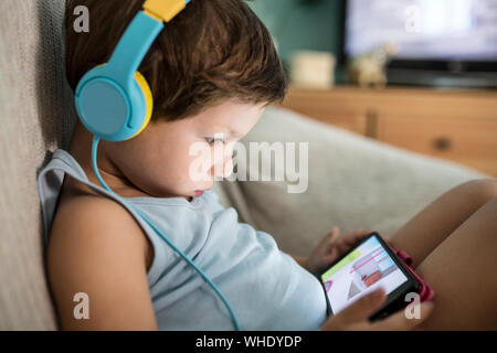 Bambini Overstimulated concetto. Troppo tempo dello schermo. 4 anni boy nelle cuffie guardare video mentre il TV è attiva Foto Stock