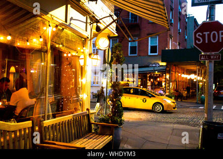 NEW YORK CITY - Agosto 24, 2019: Street scene con ristorante, le luci e le persone a notte visto da Greenwich Village, West Village di Manhattan. Foto Stock