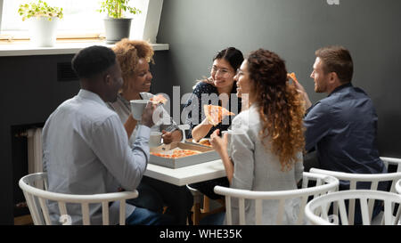 Felice multietnica office business persone aventi una divertente condividere pizza insieme Foto Stock