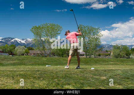 Giocatore di golf maschile nelle montagne di colpire tee-shot con conducente Foto Stock