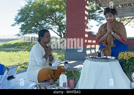 Una pia donna indù celebra la sua festa di compleanno con una puja all'aperto Servizio su Jamaica Bay nel Queens, a New York City. Foto Stock