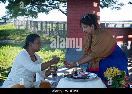 Una pia donna indù celebra la sua festa di compleanno con una puja all'aperto Servizio su Jamaica Bay nel Queens, a New York City. Foto Stock