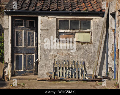 Una ruota posteriore di bicicletta & parafango sporgono dalla porta di un distressed dipendenza con rivestimenti di legno fatiscenti a Anstruther, East Neuk,Fife, Scozia, Regno Unito Foto Stock