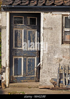 Una ruota posteriore di bicicletta & parafango sporgono dalla porta di un distressed dipendenza con rivestimenti di legno fatiscenti a Anstruther, East Neuk,Fife, Scozia, Regno Unito Foto Stock